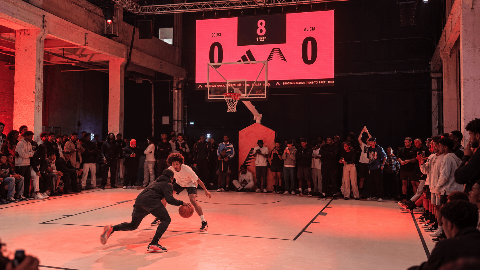 Écran LED géant de score au-dessus d'un demi-terrain de basketball lors d'un événement sportif immersif